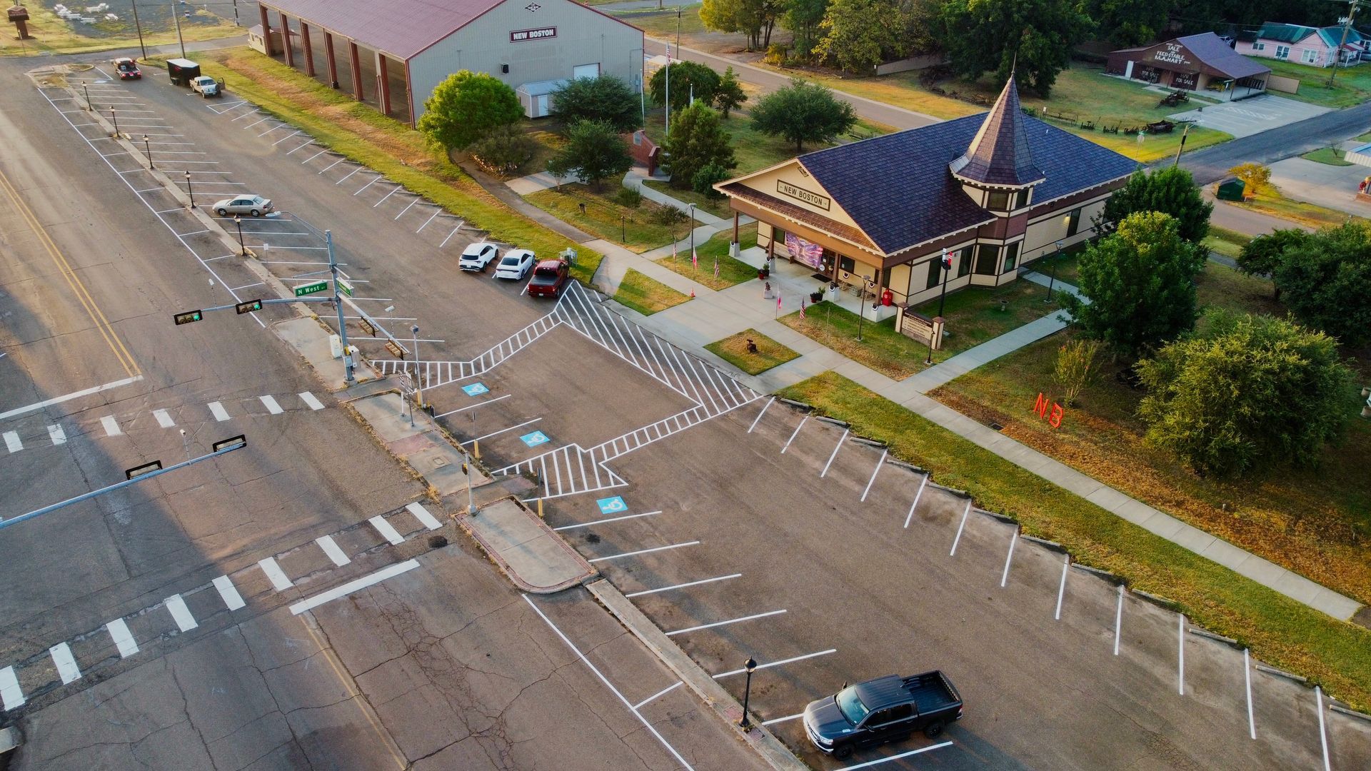 Aerial view of a street with crosswalks, a temple building, and a parked car beside a wide road.