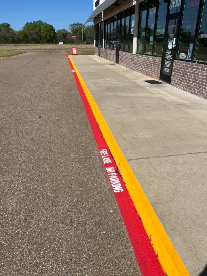 Red and yellow curb ramp beside a storefront sidewalk on a sunny day