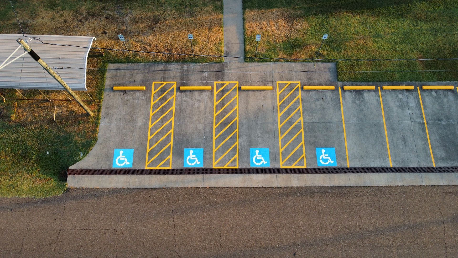 Marked accessible parking spaces beside a road, with four blue wheelchair symbols and yellow striped access aisles.