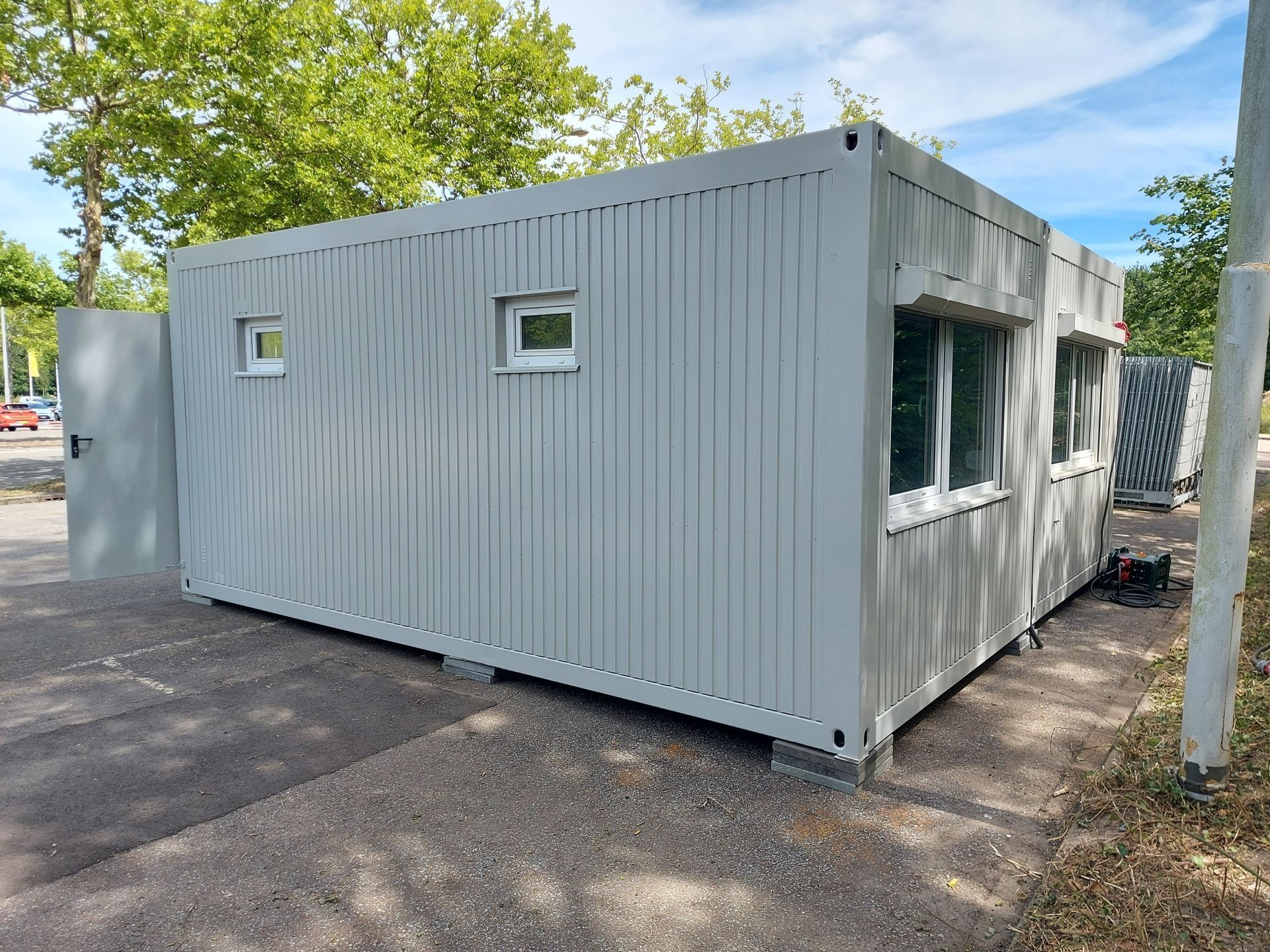 Een wit gebouw met een deur en ramen staat aan de kant van de weg.