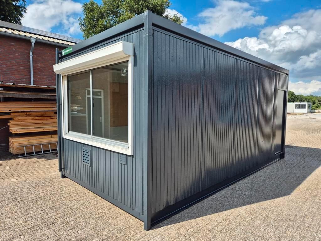 Een grijs gebouw met een raam staat op een grindperceel.