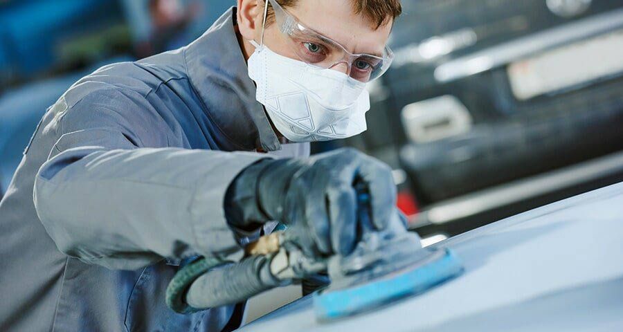 Worker sanding a car.
