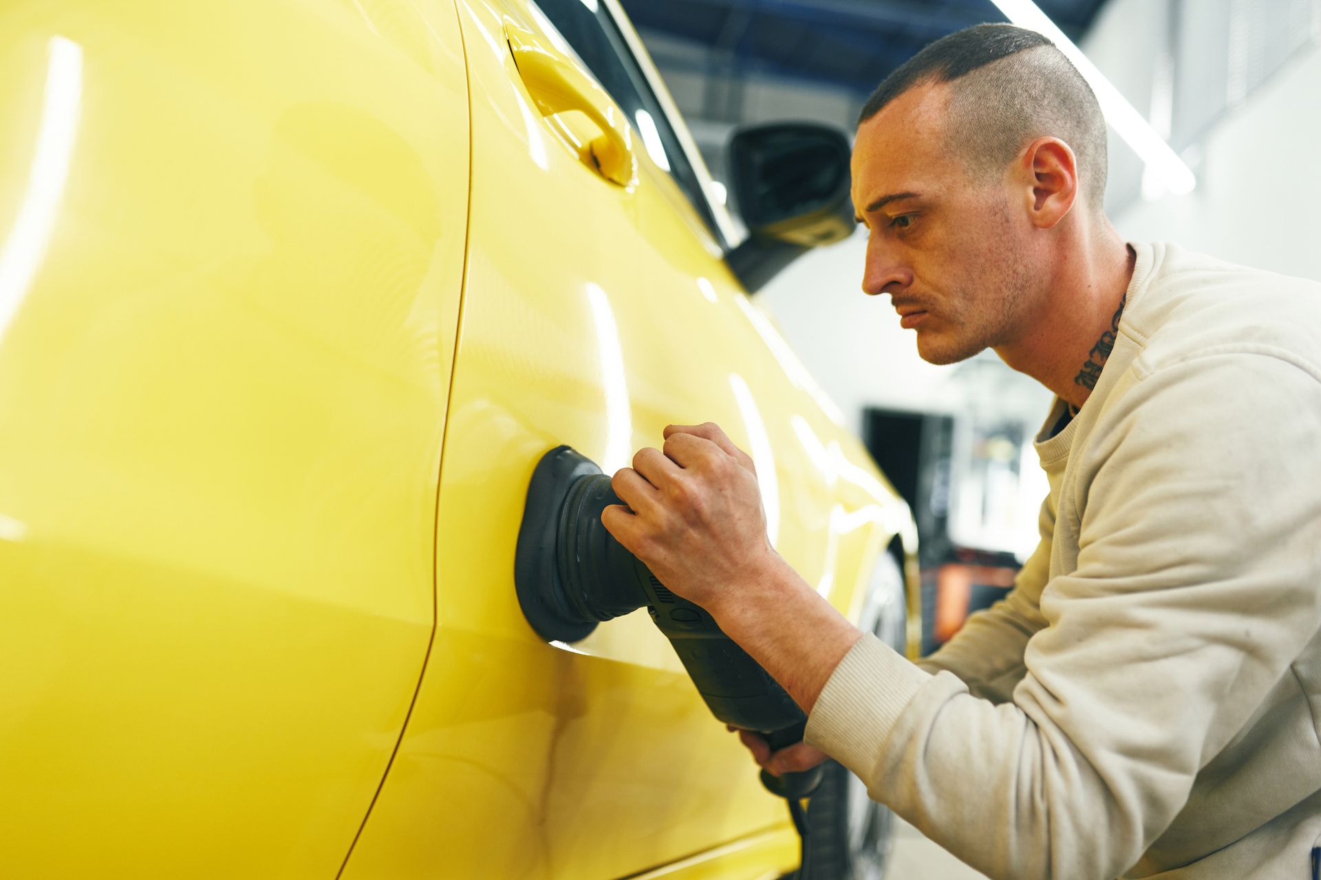 Mechanic polishing yellow car Mechanic polishing yellow car
