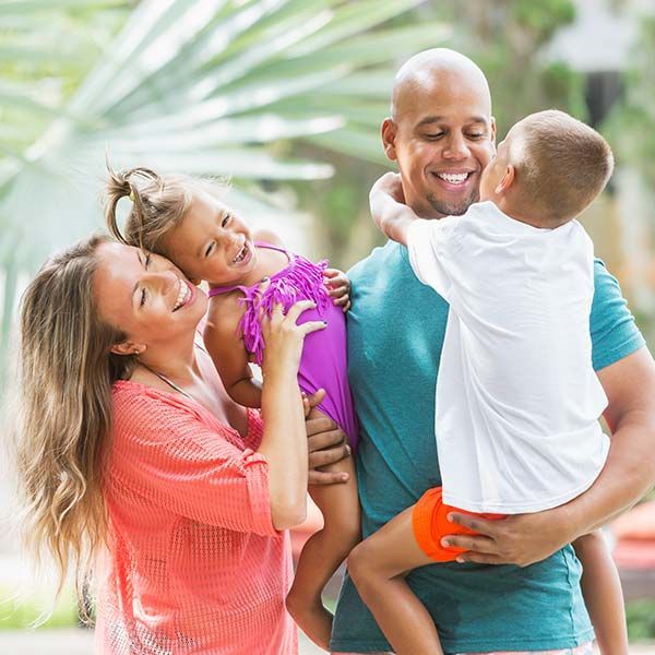 Smiling family hugging outdoors in colorful shirts in a bright garden
