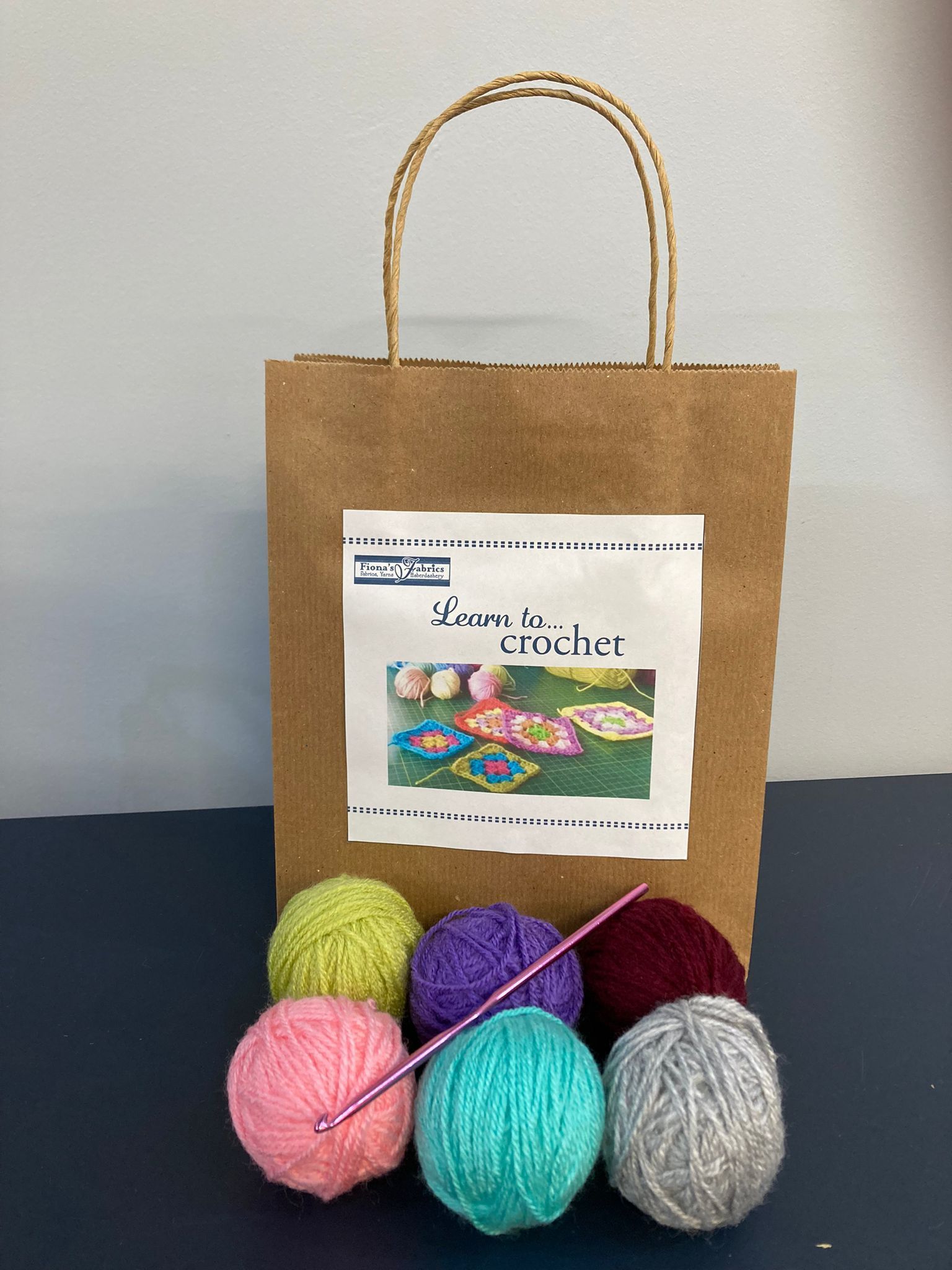 A brown bag filled with balls of yarn and a crochet hook.