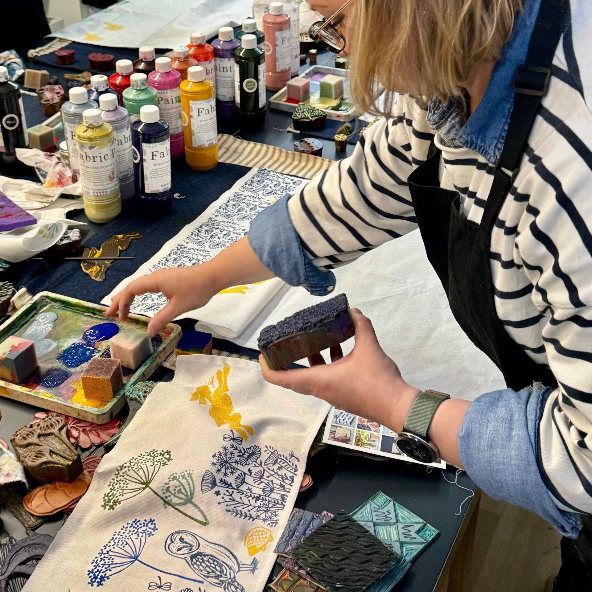 Two women are sitting at a table painting.