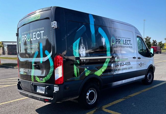 Une camionnette commerciale noire garée sur un parking extérieur, arborant un grand logo bleu et vert représentant un bouton d'alimentation et la marque Prulect.