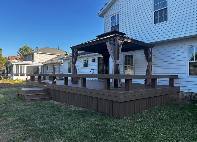 Backyard deck with a pergola attached to a white house on a sunny day