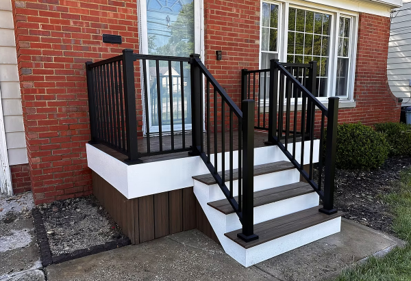 Front steps with black railings and white trim leading to a brick house entrance.