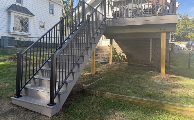 Backyard deck stairs with black railing leading down to a grassy yard