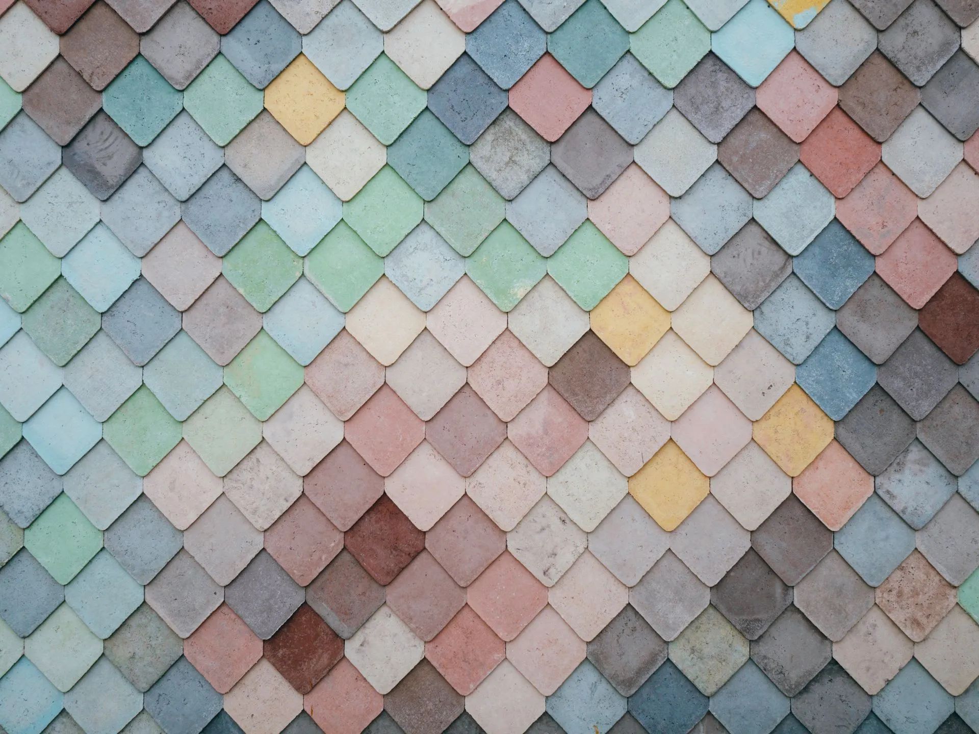 Colorful, textured wall composed of diamond-shaped tiles in various pastel shades.