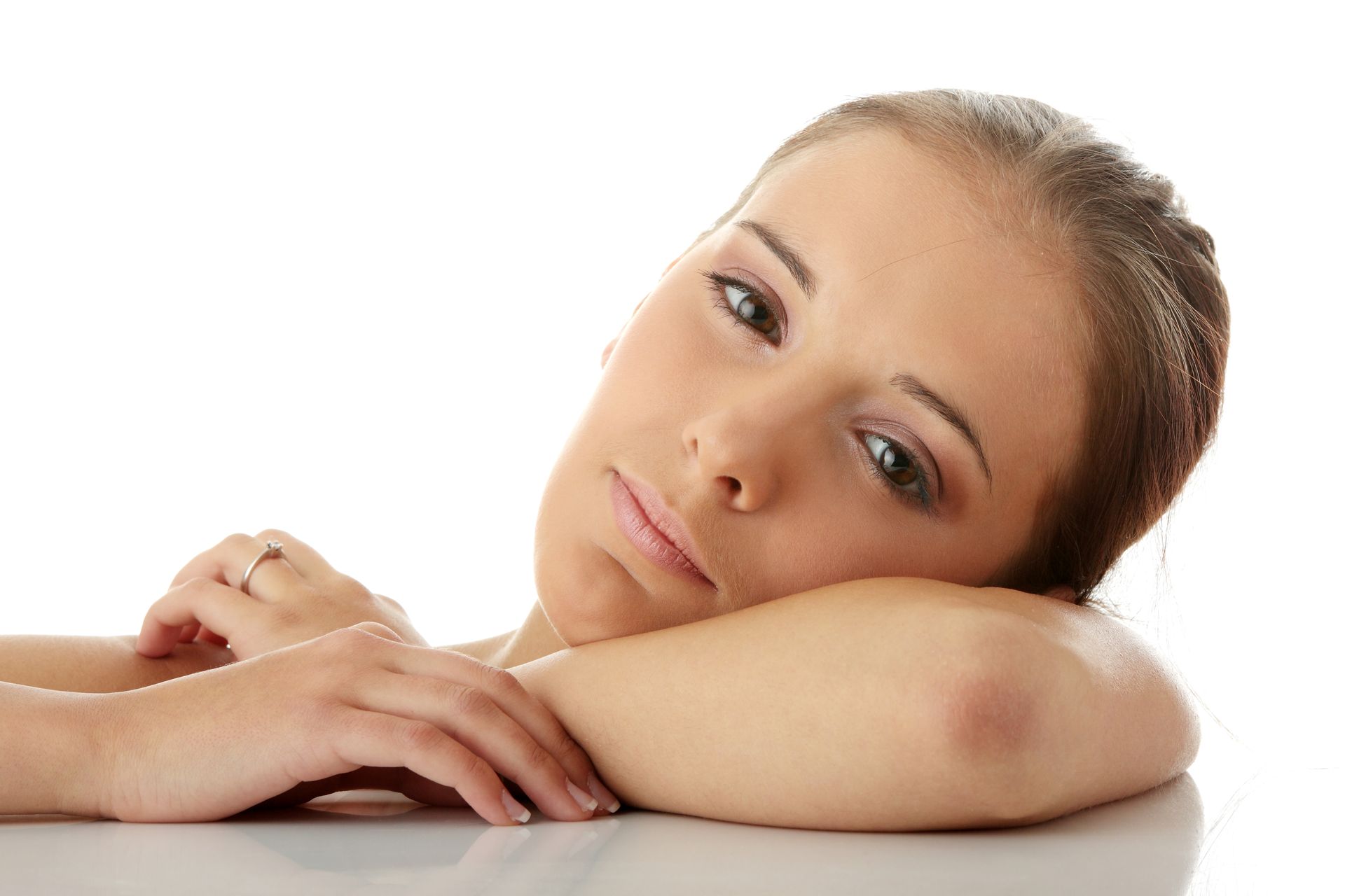 Woman rests chin on arm, looking at the viewer. Soft lighting. White background.