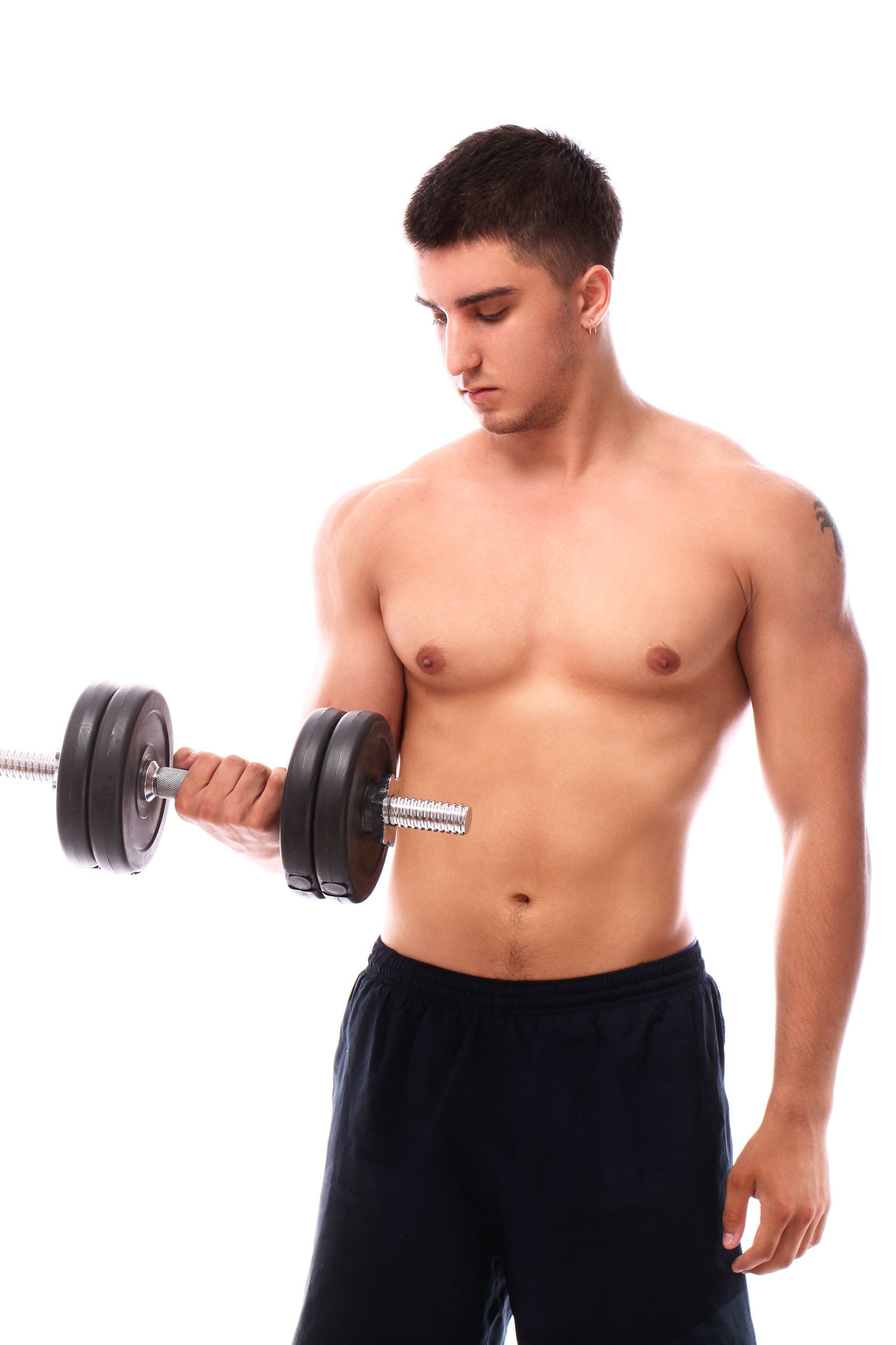 Man lifting a dumbbell, shirtless, in a white studio.