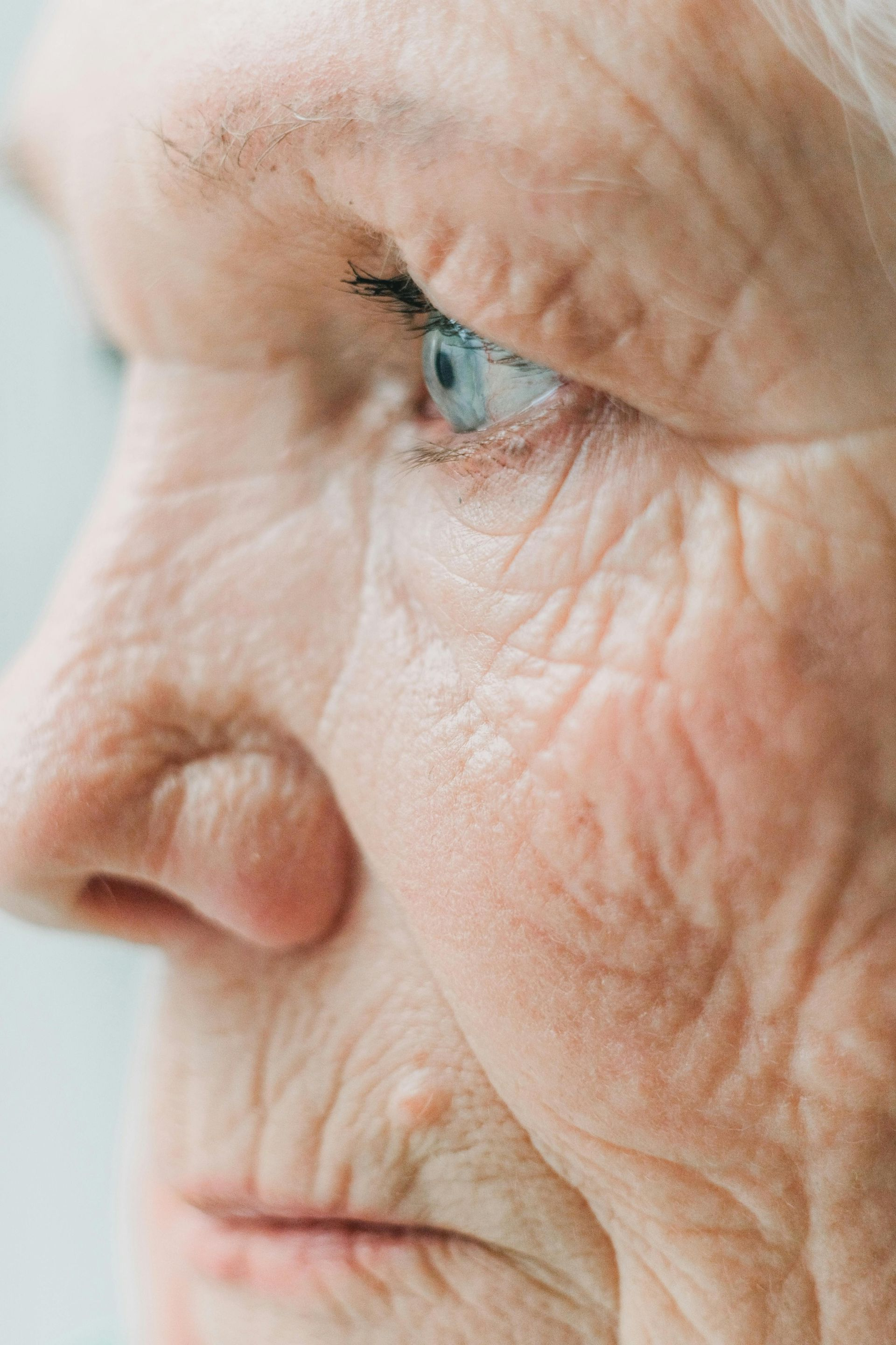 Close-up of an elderly woman's face in profile, showing wrinkles and blue eyes.