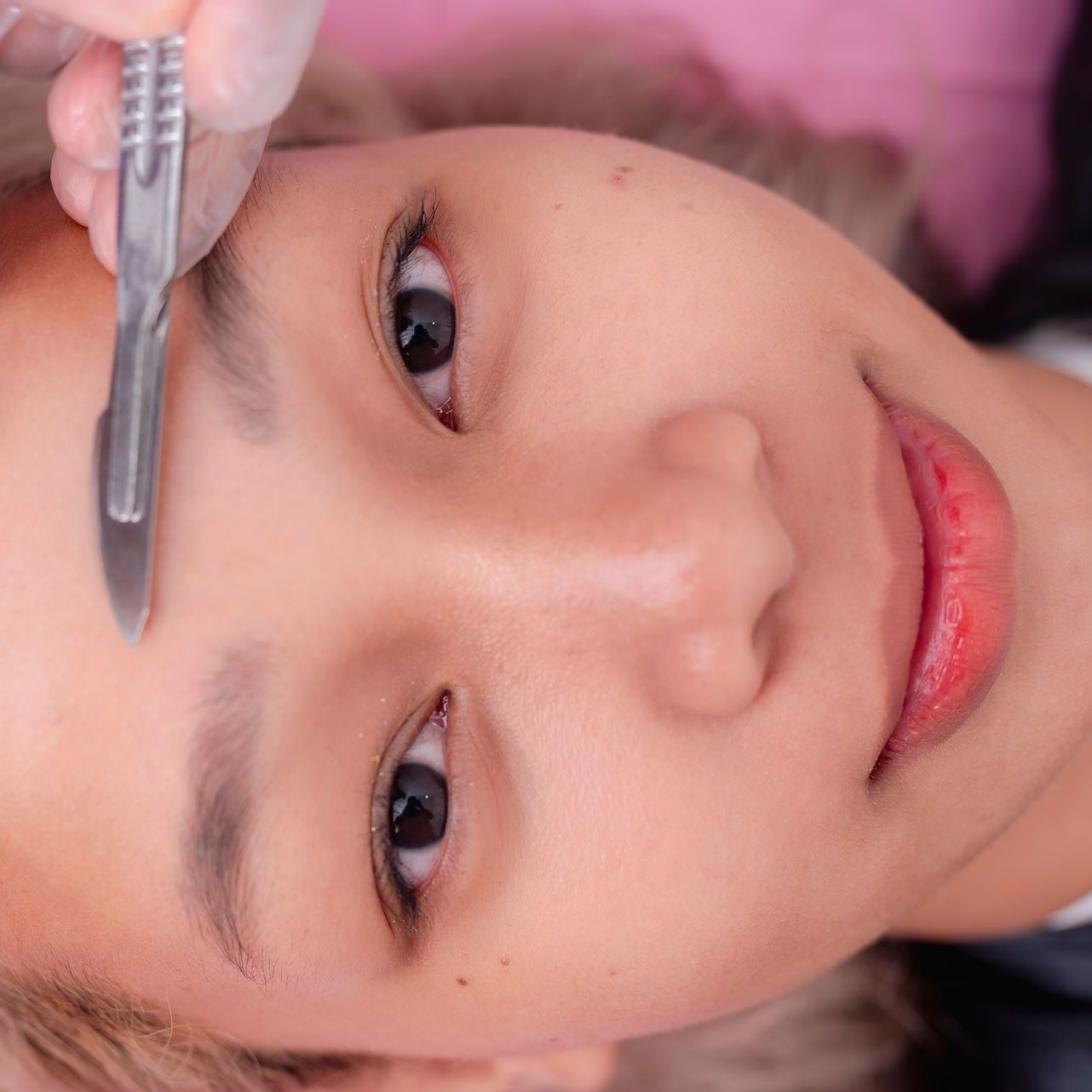 Person getting eyebrow shaping with a scalpel.