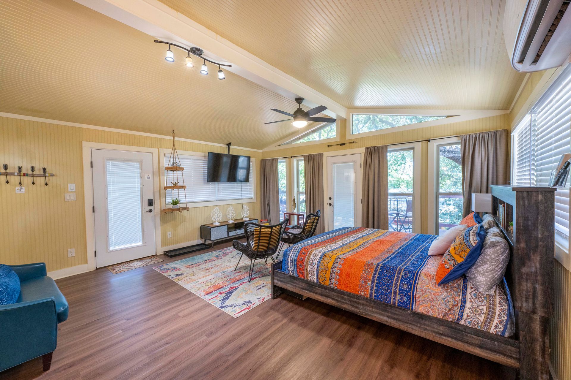 Cozy cabin bedroom with a bed, TV, seating area, and wooden floors.