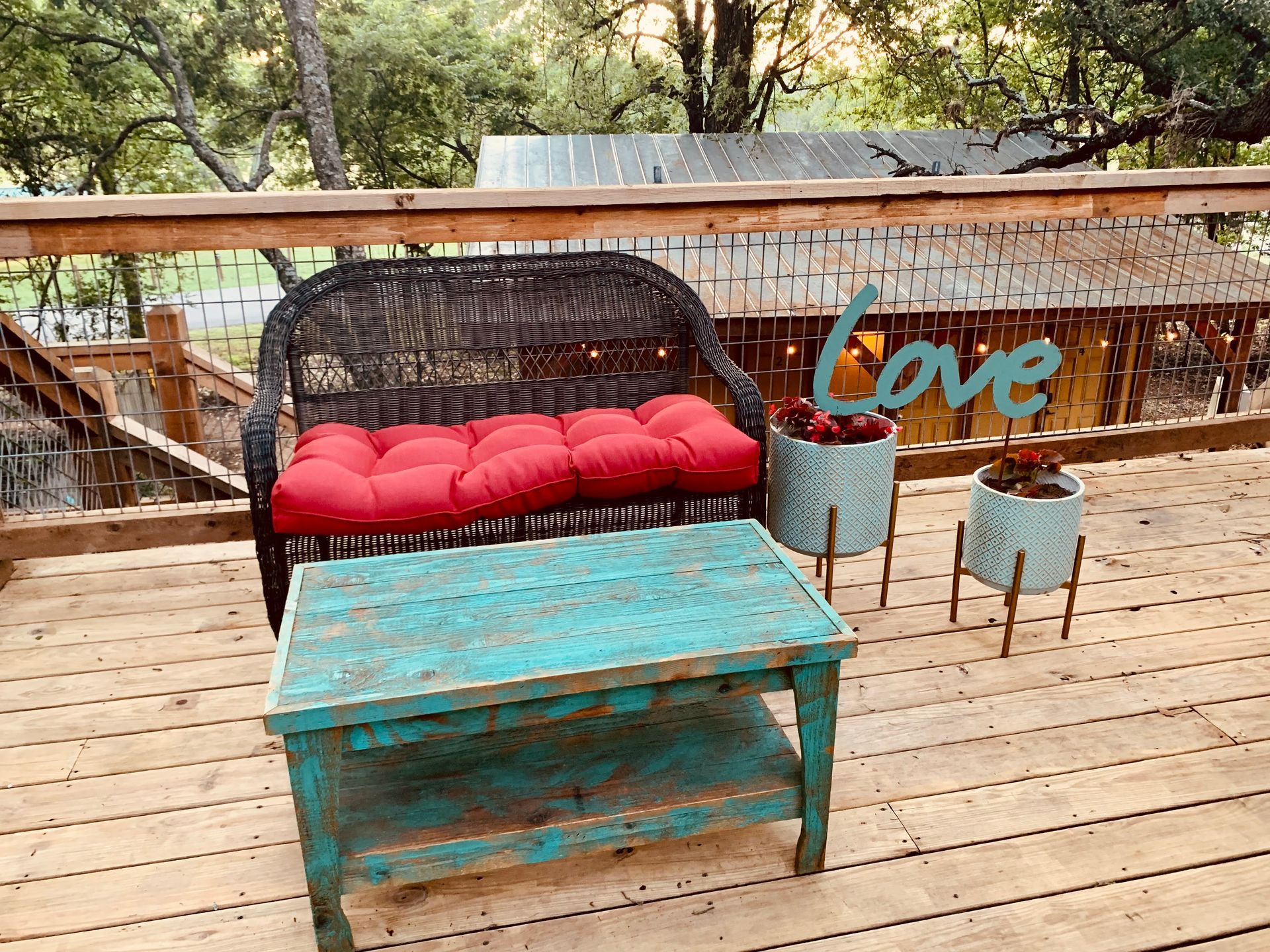 Outdoor seating area with turquoise table, wicker couch with red cushions, and 
