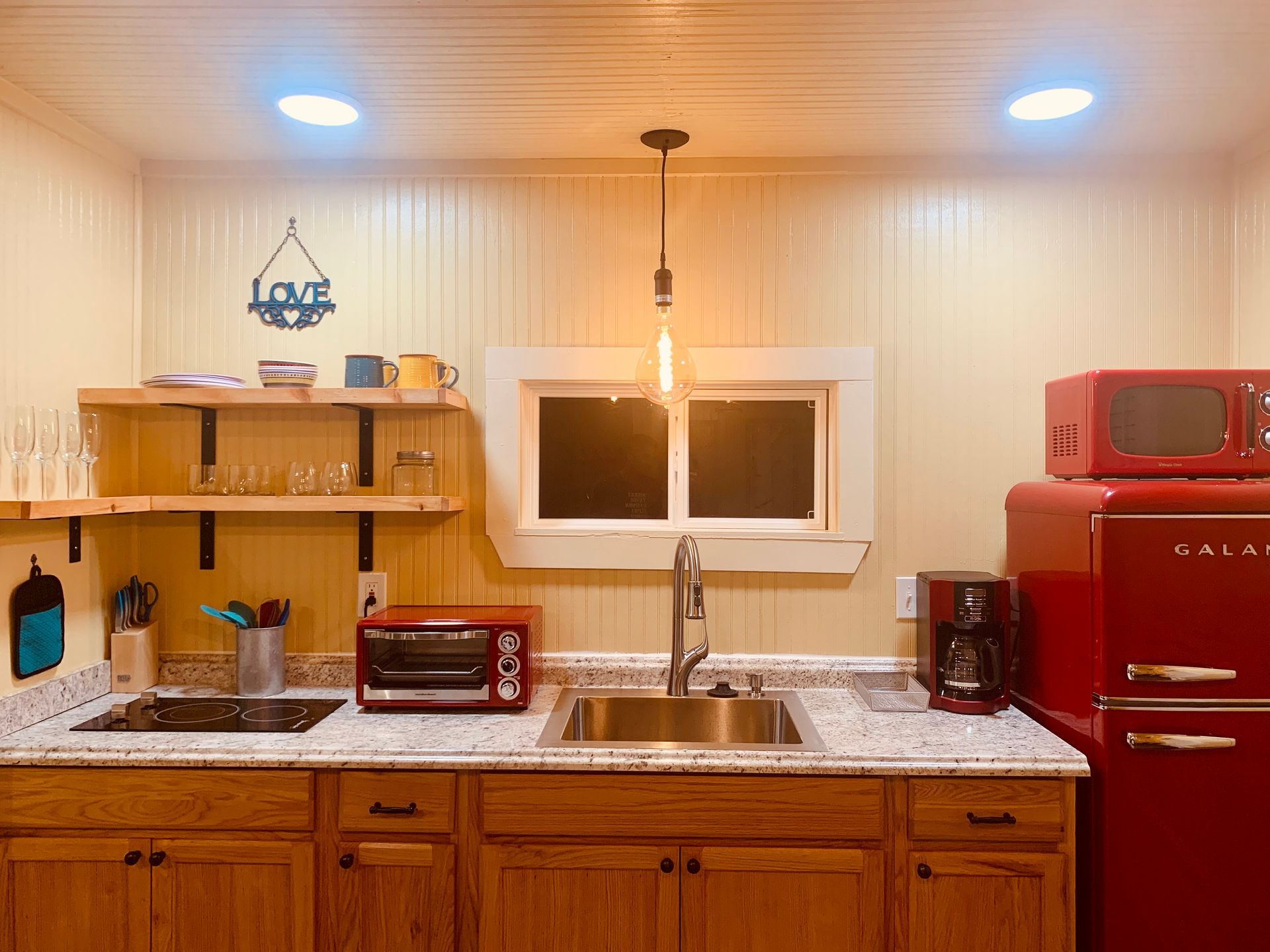 Small kitchen with red appliances, wooden cabinets, and a granite countertop.