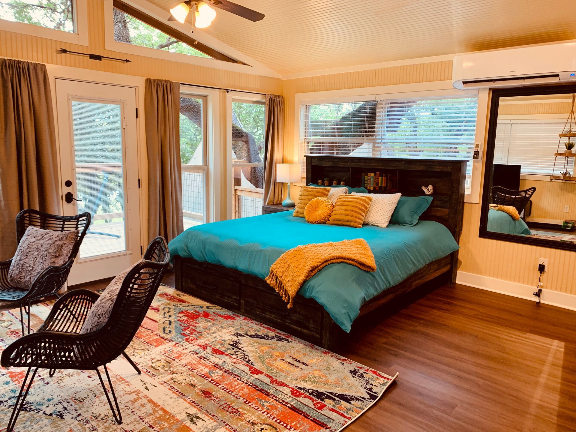 Bedroom with bed, rug, chairs, and large window.