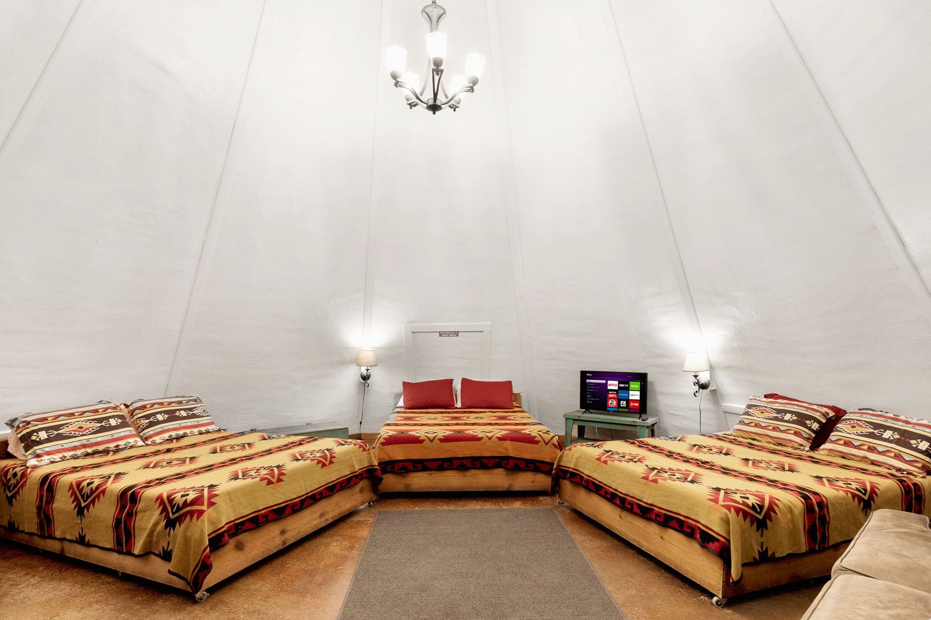 Interior of a teepee-shaped room with three beds and a television.