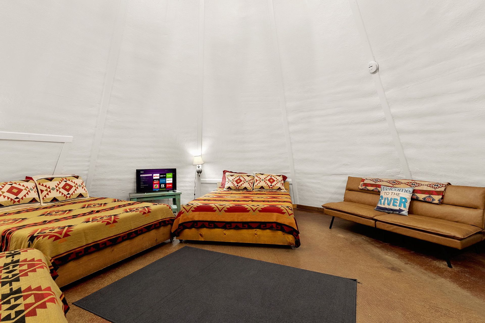 Interior of a dome-shaped room with beds, a futon, and a TV.