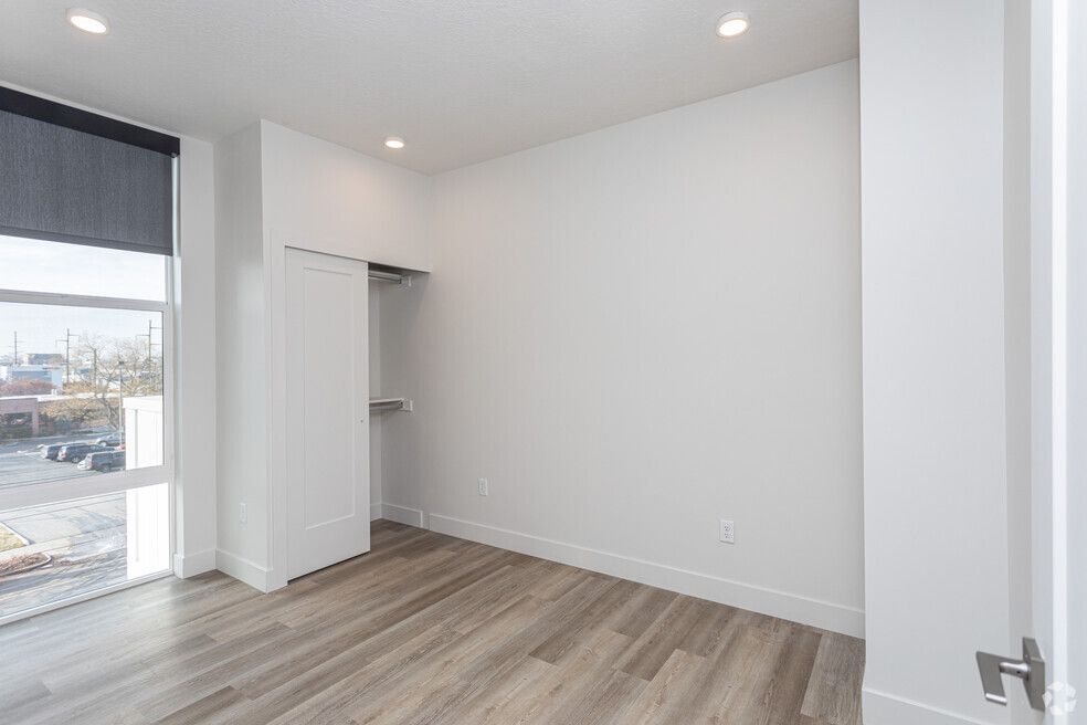 an empty bedroom with hardwood floors and a large window .