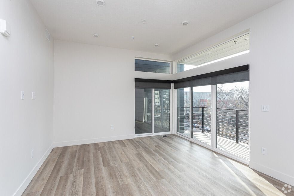 an empty living room with hardwood floors and sliding glass doors .