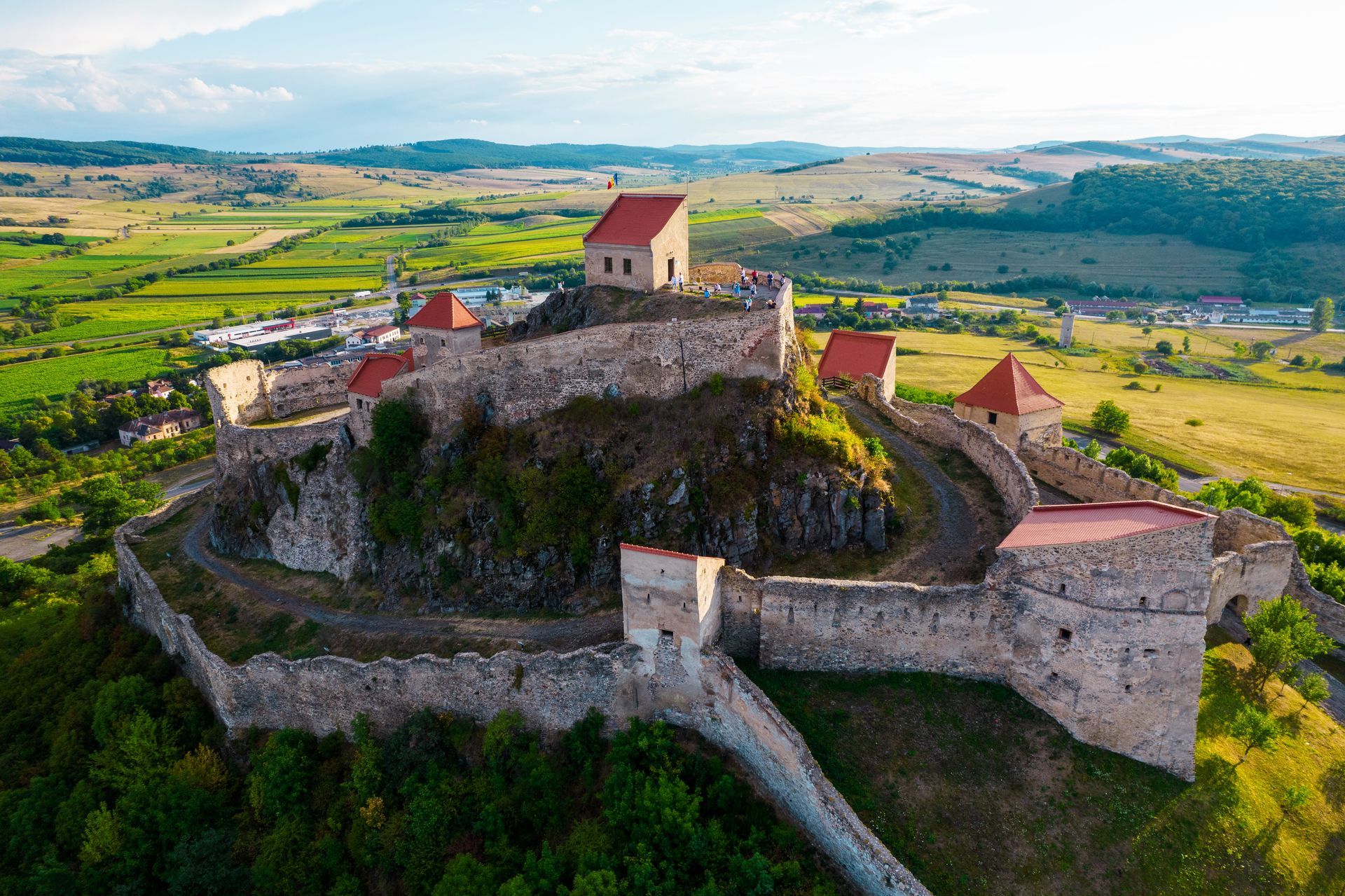 An aerial view of a castle on top of a hill in the middle of a field.