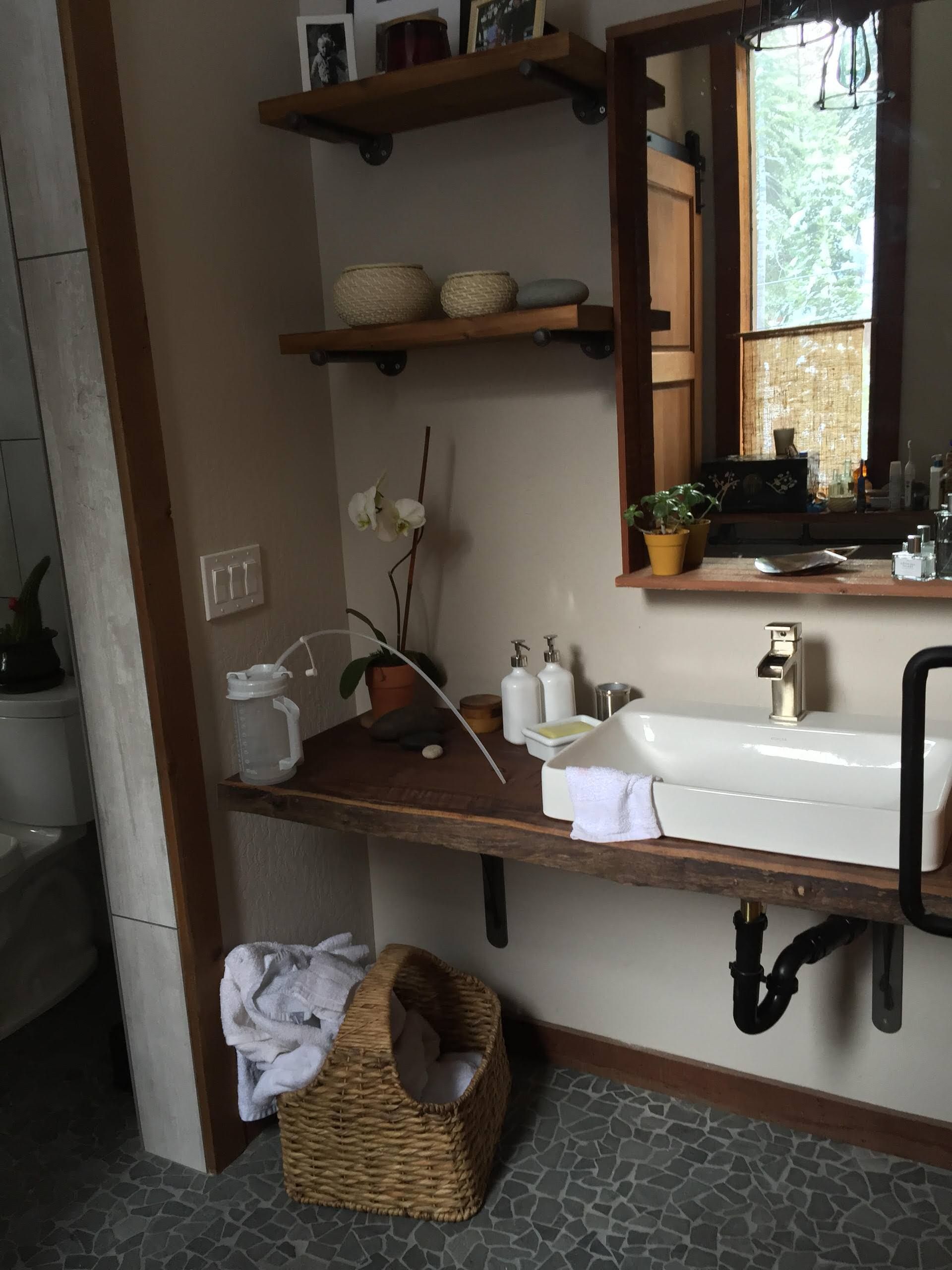 Bathroom with floating wood shelves, white sink, woven basket, and window.