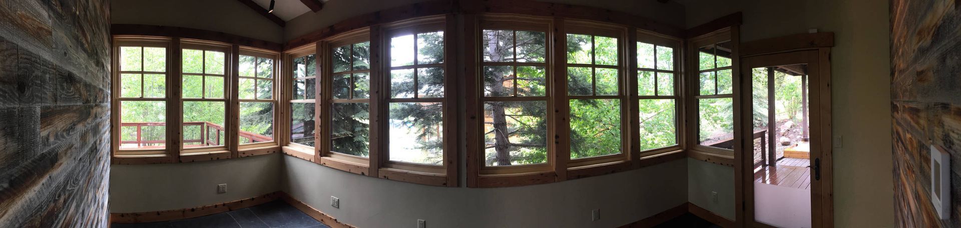 Sunroom with many windows, stone walls, and a view of trees.