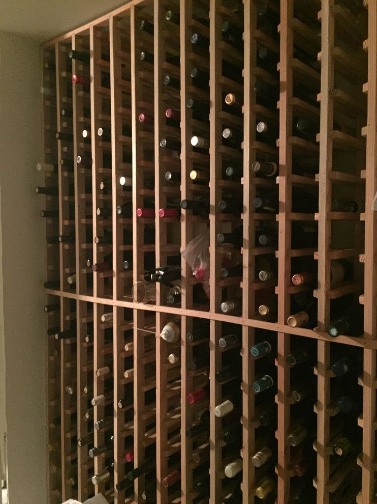 Wooden wine rack filled with numerous wine bottles, in a wall-mounted structure.