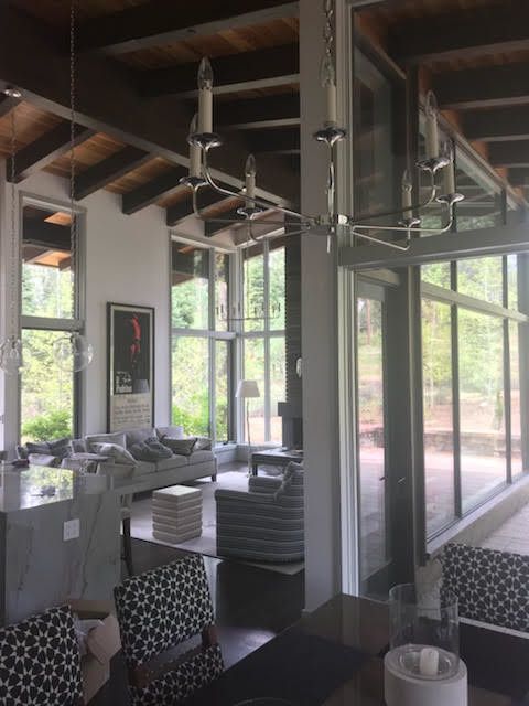 Modern interior with large windows, chandelier, sofa, and outdoor view.