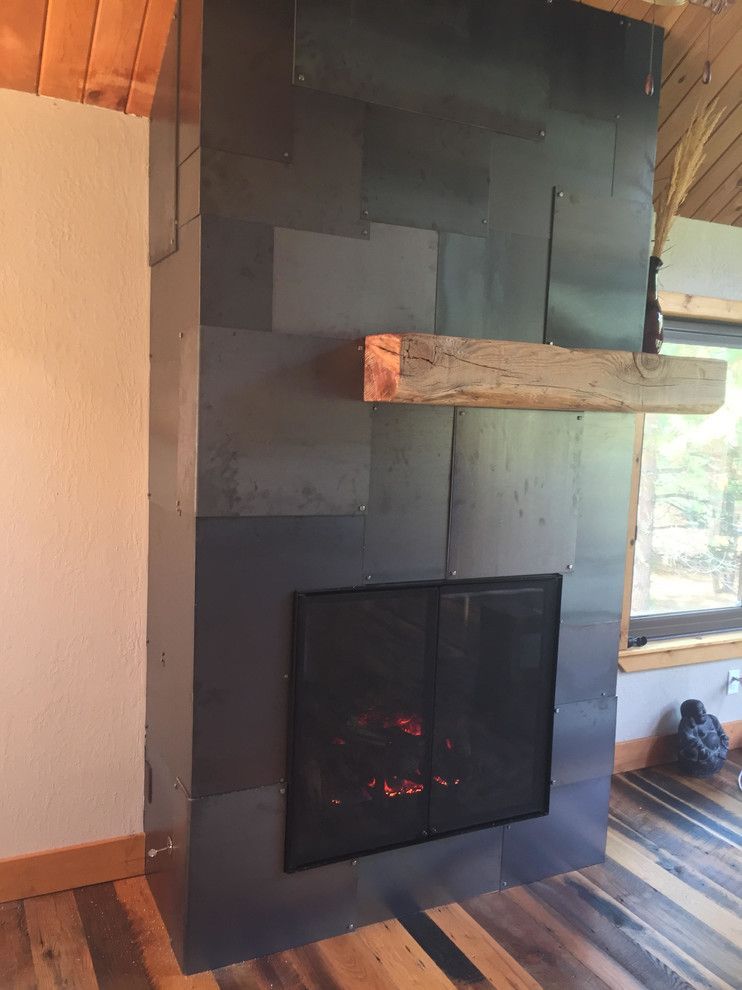 Black tiled fireplace with wood beam mantel and fire.