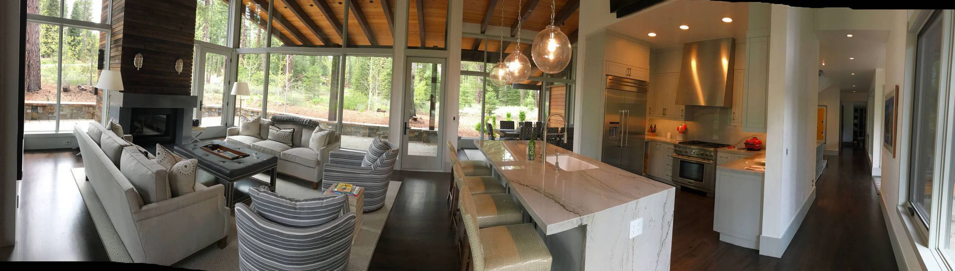 A modern home interior with a living room, dining area, and kitchen, featuring large windows and neutral tones.