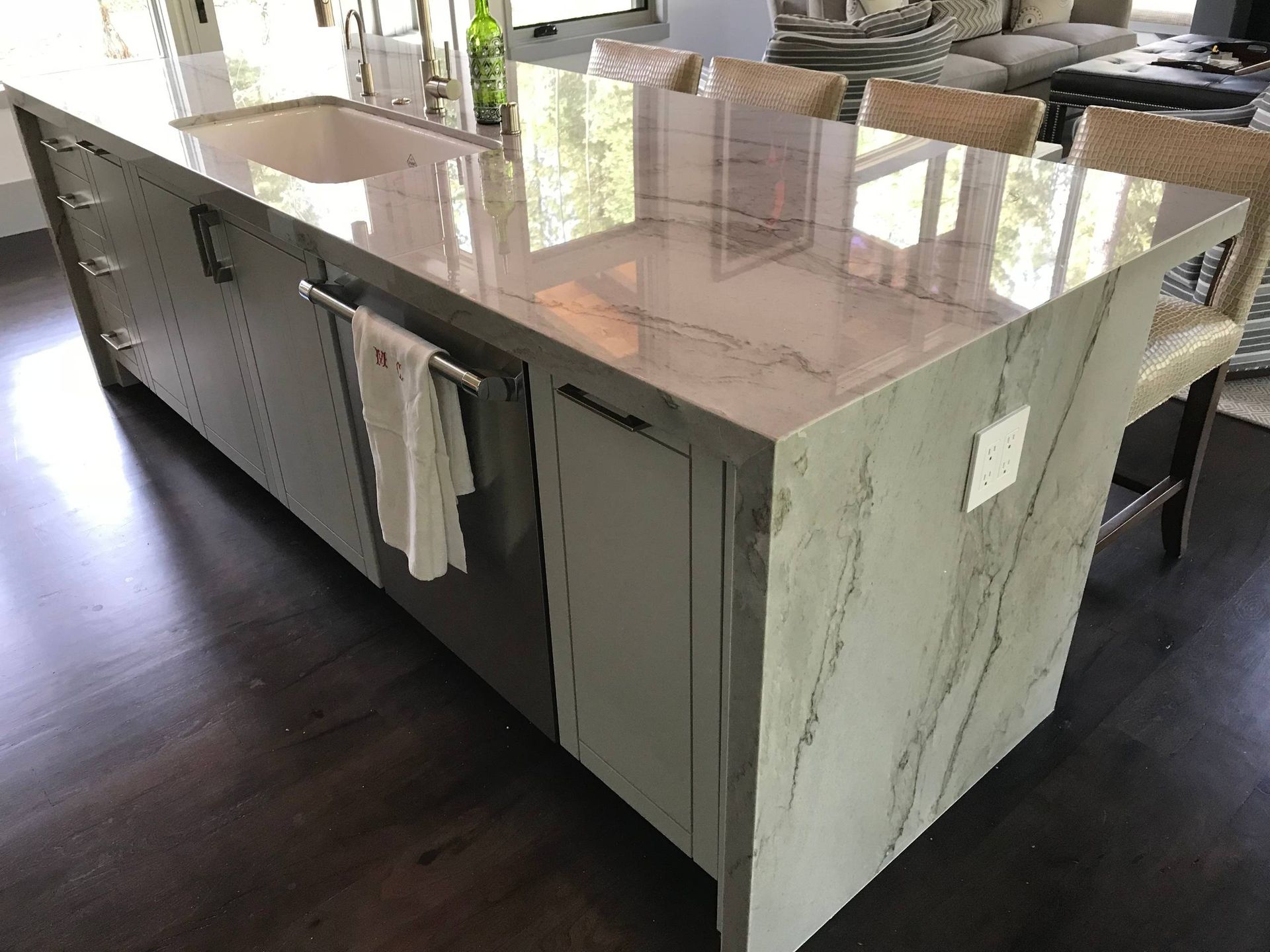 Kitchen island with light gray cabinetry, a marble countertop, and a built-in sink.