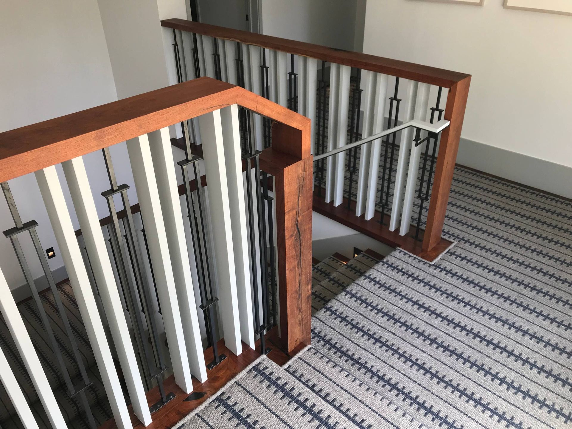 Staircase with wooden handrails and spindles, carpeted flooring, and a neutral-toned setting.