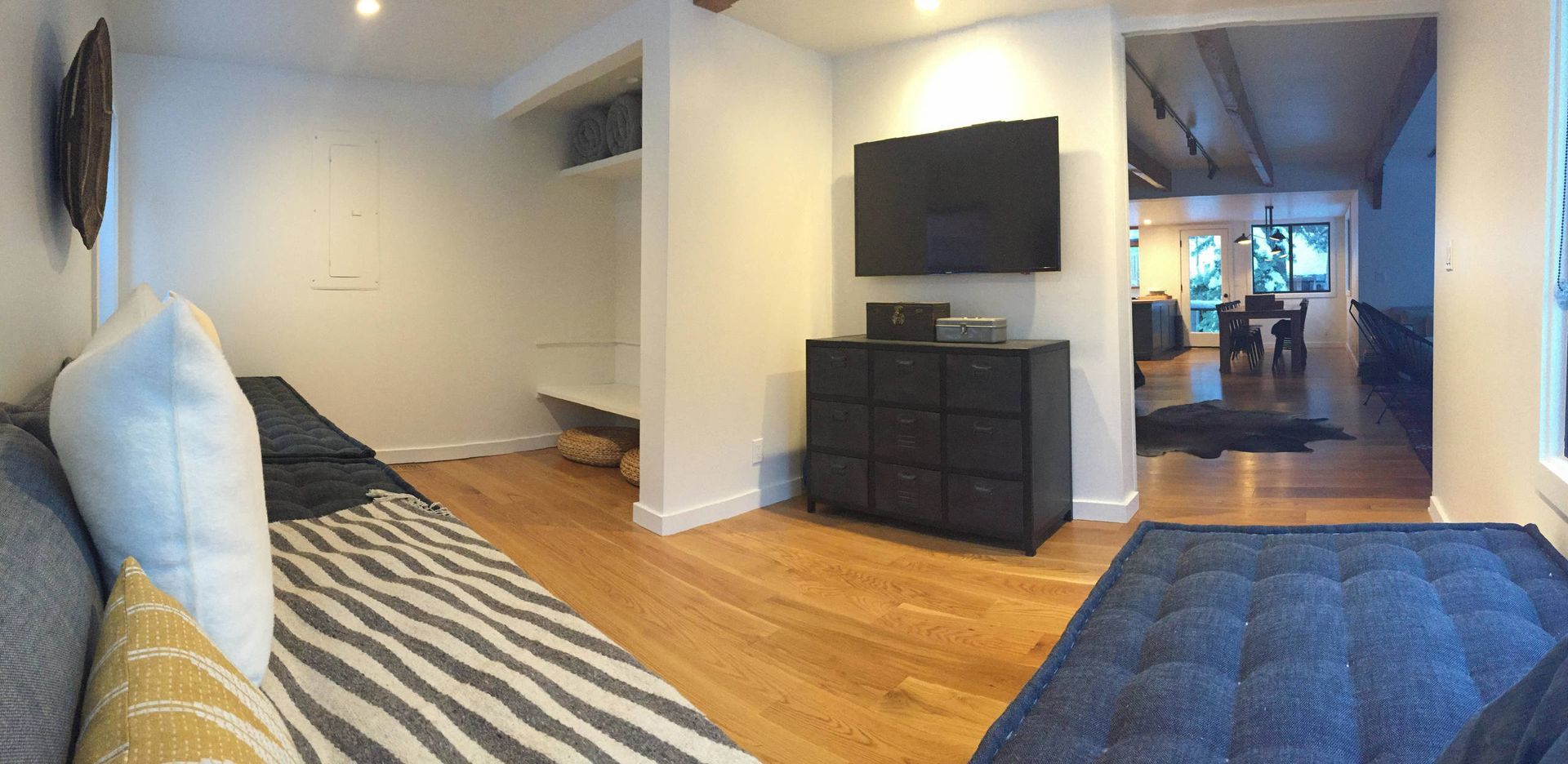 Living room with a sofa, TV, and black dresser. Hardwood floors and doorway to another room.