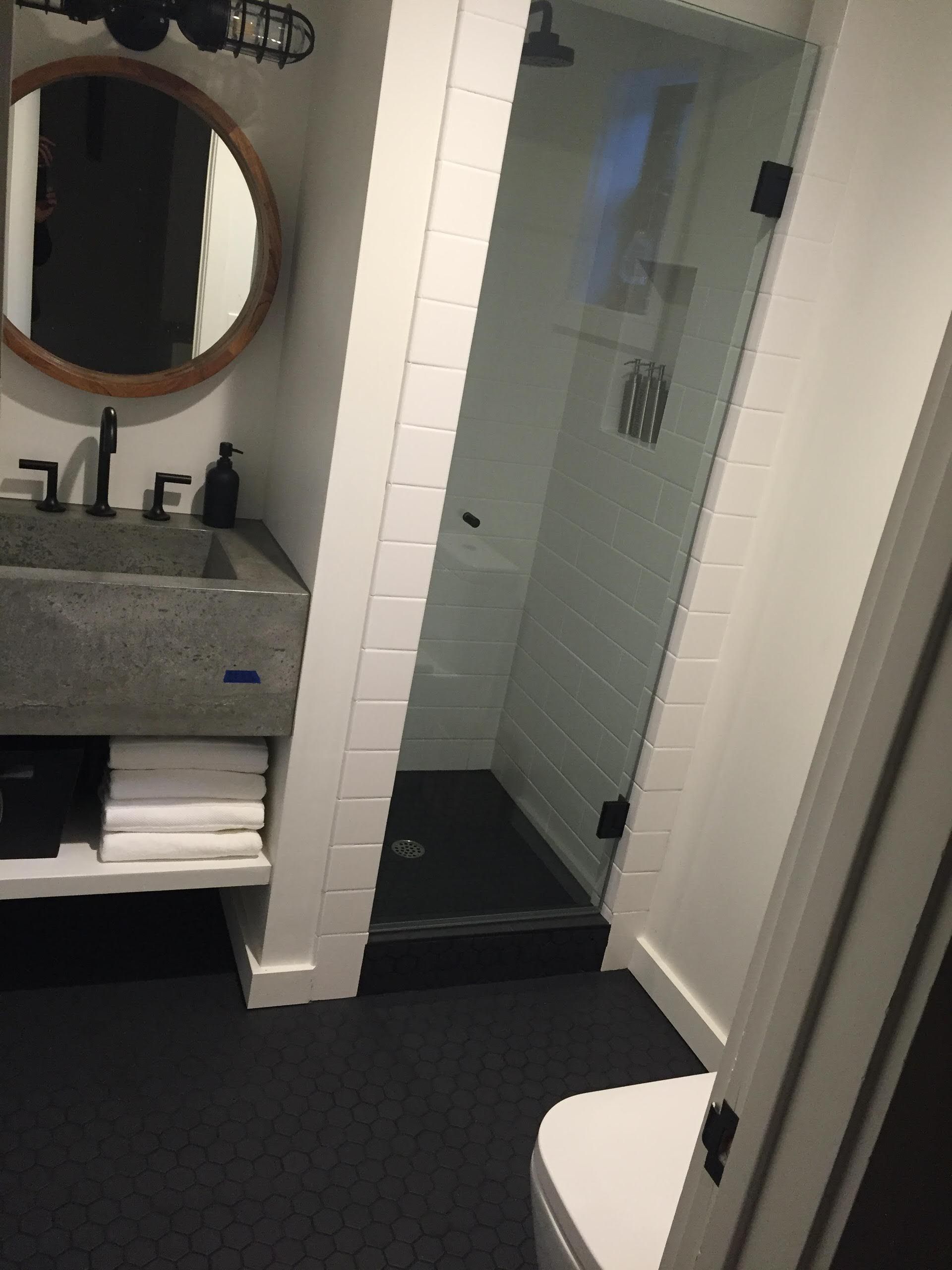 Bathroom with gray sink, white subway tile shower, and black floor.