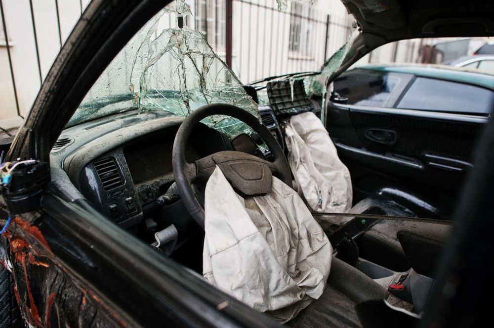 Damaged car interior with broken windshield and deployed airbag after a crash