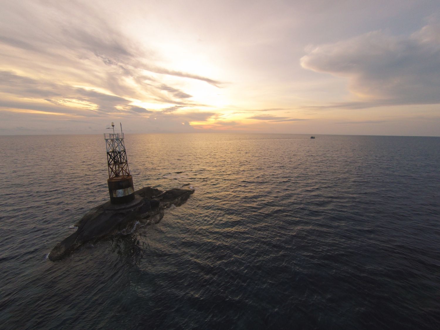 Submarine surfacing at sunset on a calm ocean, with a buoy and birds nearby