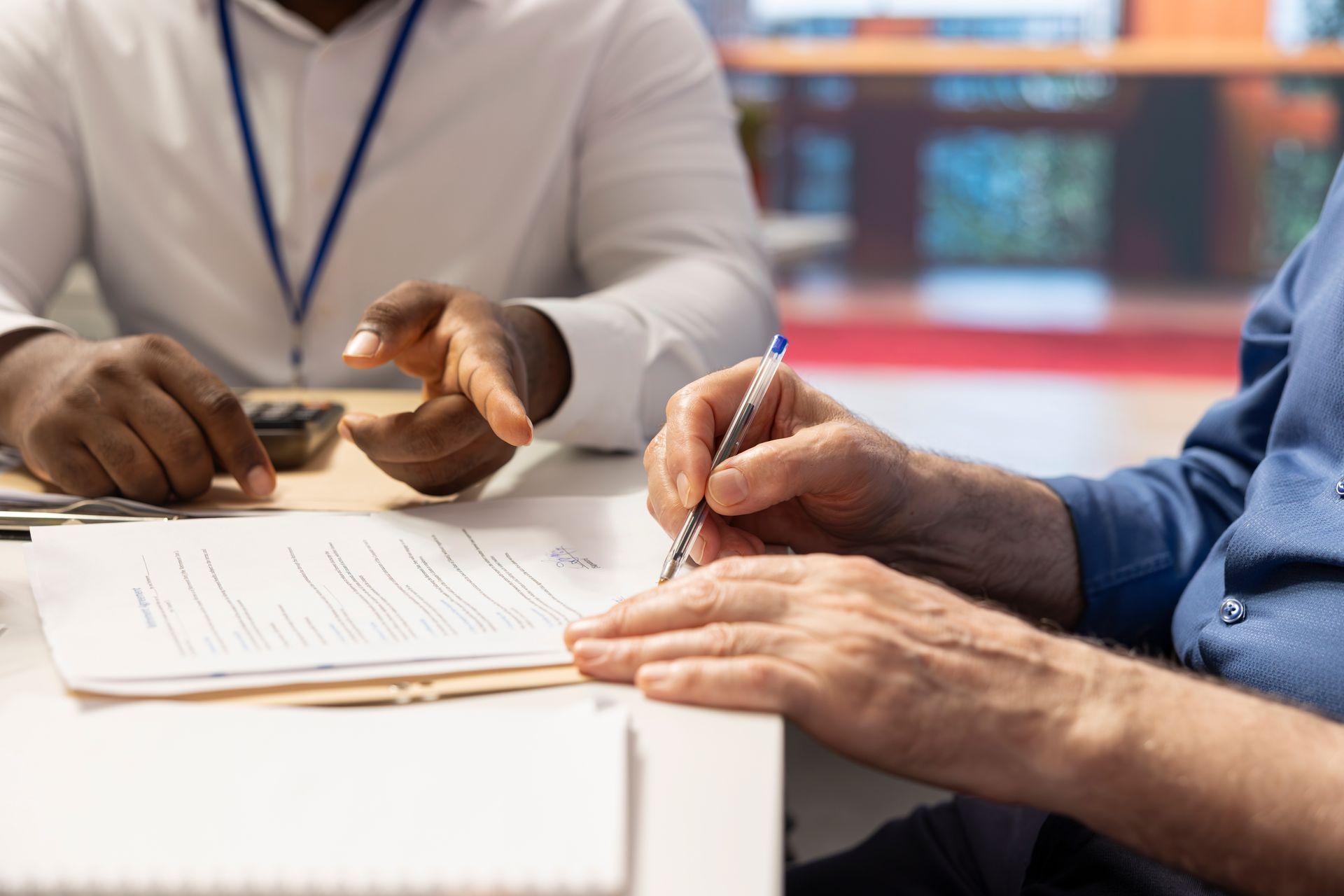 Two people reviewing documents and signing paperwork at a table