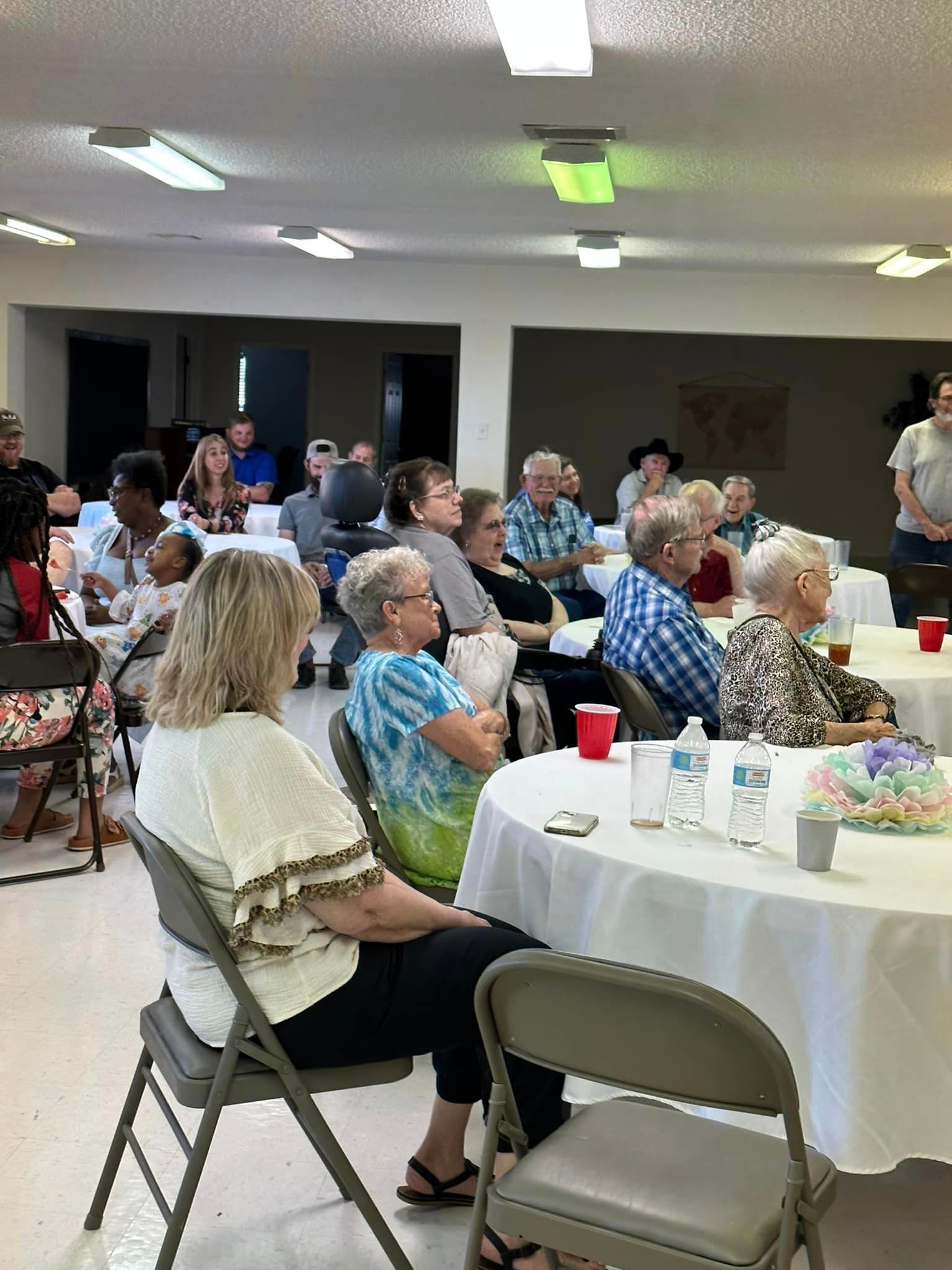 People seated at tables in a room, attending an event.