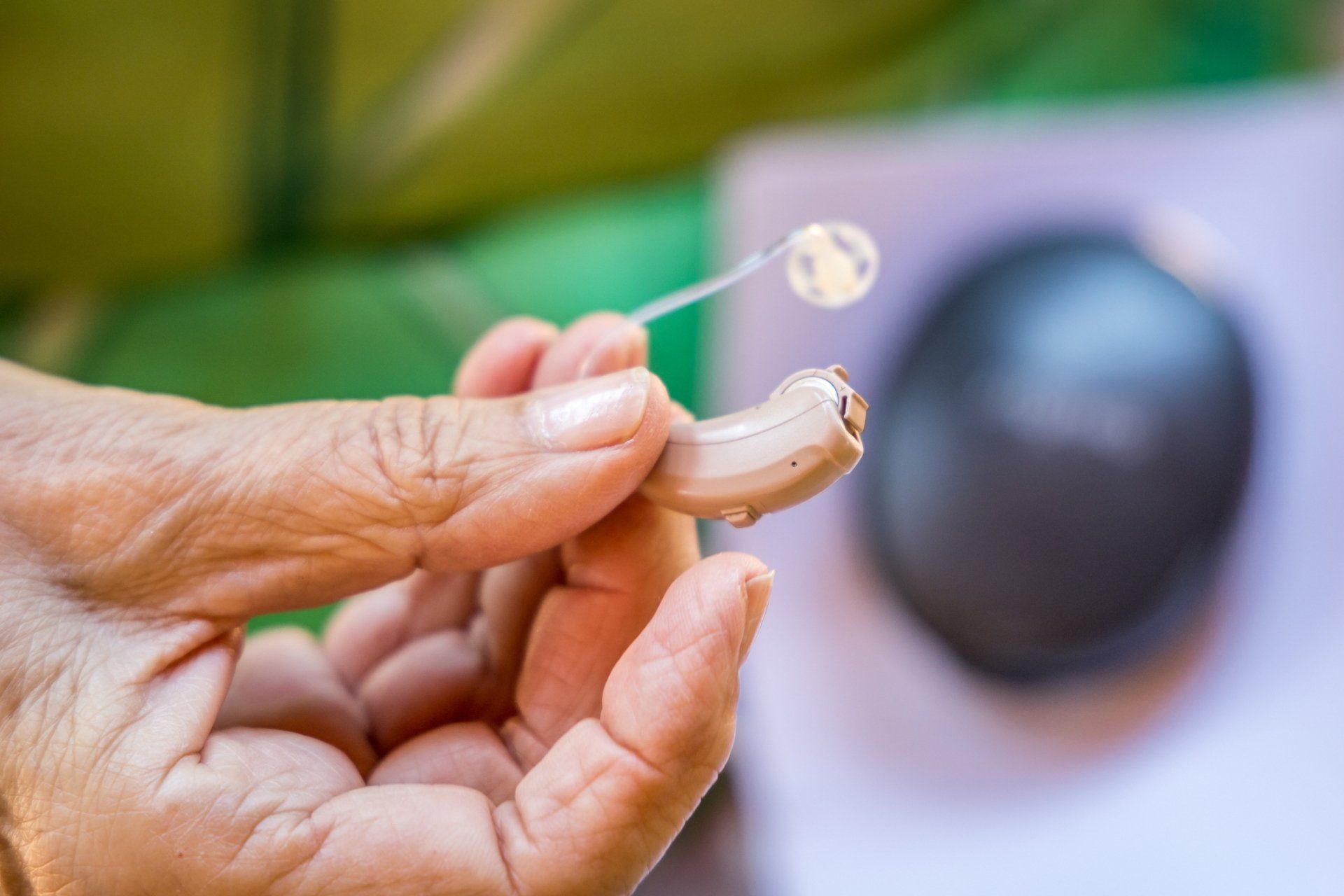 Senior Woman Holding A Hearing Aid — Sewell, NJ — Hearing Hut LLC Senior Woman Holding A Hearing Aid — Sewell, NJ — Hearing Hut LLC