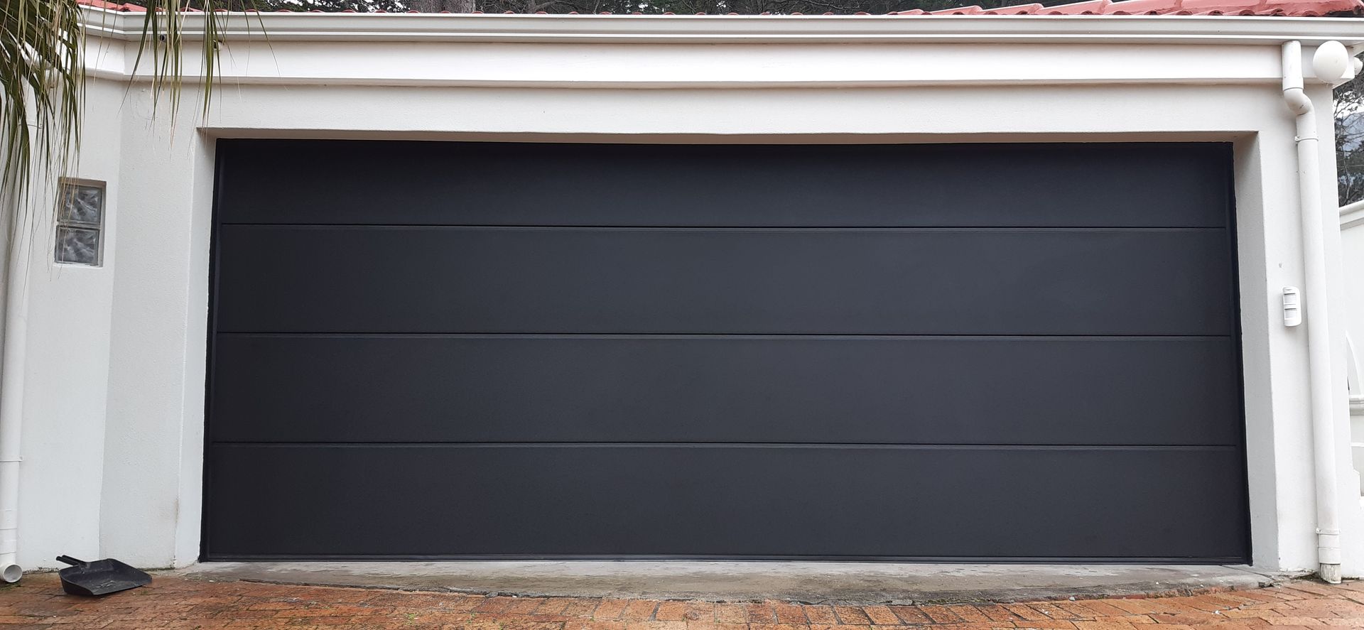 A dark grey garage door with horizontal lines, set in a white framed opening.