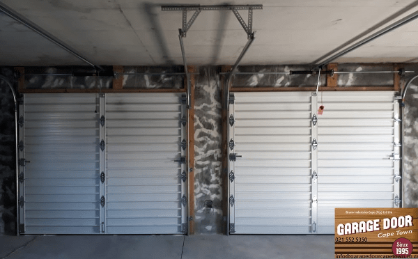 Two closed garage doors in a garage, made of horizontal metal panels.