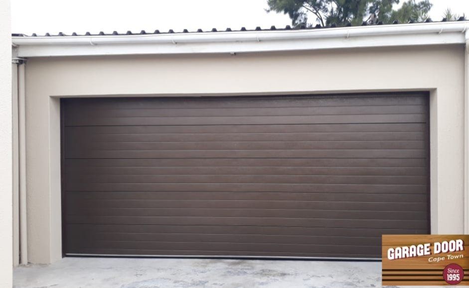 Brown horizontal-panel garage door on a beige building.