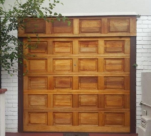 Wooden garage door with a grid pattern, set against a brick wall.