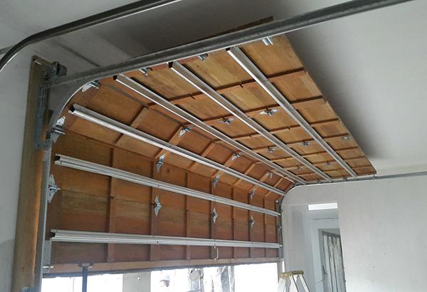 Garage door interior with curved wooden panels and metal tracks.
