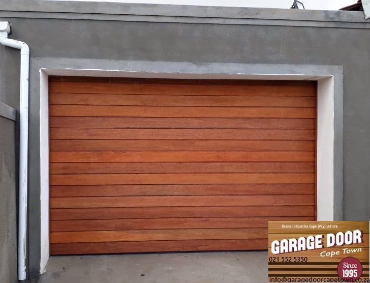 Wooden garage door with a white frame, set in a gray wall.