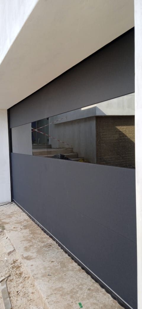Dark gray window with visible reflection and a white wall. Concrete ground.